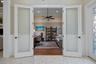 French-style double doors featuring frosted glass panels and dark hardware, wood-finish flooring, recessed lighting, and a ceiling fan