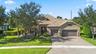 Stucco exterior residence featuring stone veneer accents, a multi-car garage, a paver driveway, and a tiled roof