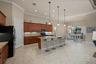 Kitchen featuring cabinetry with stained wood finish, stone-surfaced countertops, a center island with bar seating, pendant lighting, and tile floorin