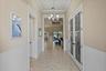 Foyer featuring white beadboard wainscoting, crown molding, tile flooring, a multi-arm chandelier, and glass-paneled French doors with decorative etch