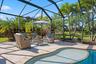 Screen-enclosed patio featuring paver decking, an in-ground pool, and mature palm trees