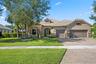 Single-story residence featuring a stone and stucco facade, concrete tile roof, paved driveway, and arched entryway