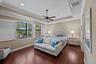 Tray ceiling featuring crown molding, dark wood-finish flooring, recessed lighting, ceiling fan, and plantation shutters