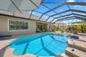 Screened-in pool area featuring a paver deck, integrated step entry, and a covered lanai