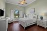 High ceilings with crown molding, wood-finish flooring, and an arched window featuring plantation shutters
