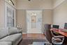 Room featuring high ceilings, wood-finish flooring, crown molding, and a wide doorway with decorative trim