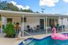 Covered patio featuring a painted concrete floor, a built-in exterior bar, and a rectangular swimming pool with tiled coping and metal handrails
