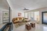 Living area featuring terrazzo flooring, a fireplace with a painted stone hearth, a central ceiling fan, and a glass-panel entry door