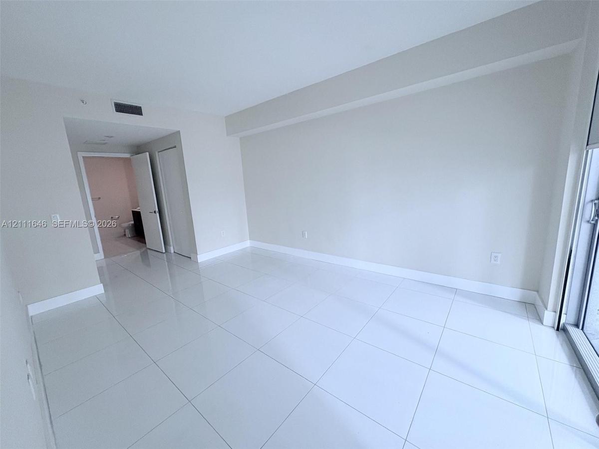 Neutral-toned interior space featuring polished tile flooring, recessed ceiling lighting, and glass sliding doors
