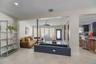 Open-concept interior featuring light-toned stone-finish flooring, recessed lighting, and a painted brick built-in planter with a central support pill