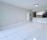 Large-format white tile flooring, high-gloss white cabinetry, integrated stainless steel kitchen appliances, peninsula countertop, and flush-mount lig
