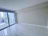 Large-format porcelain tile flooring, floor-to-ceiling glass sliding doors, and access to a private balcony