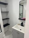 Built-in black shelving, modern vanity with white countertop, integrated sink, matte black faucet, and rectangular mirror with black frame