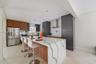 Kitchen featuring custom two-tone cabinetry, waterfall-edge stone island, built-in stainless steel appliances, and professional-grade range hood
