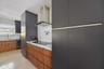 Kitchen featuring custom flat-panel cabinetry with wood-finish lower cabinets and matte charcoal upper cabinetry, stainless steel range hood, integrat