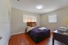 Room featuring wood-finish flooring, dual windows with vertical blinds, and a built-in closet with louvered doors