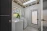 Utility room featuring exposed ceiling joists, tile flooring, a window, and an exterior door with integrated security screening