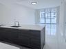 Kitchen island featuring dark wood-finish cabinetry, a white countertop, and an undermount sink with a gooseneck faucet, set against white tile floori