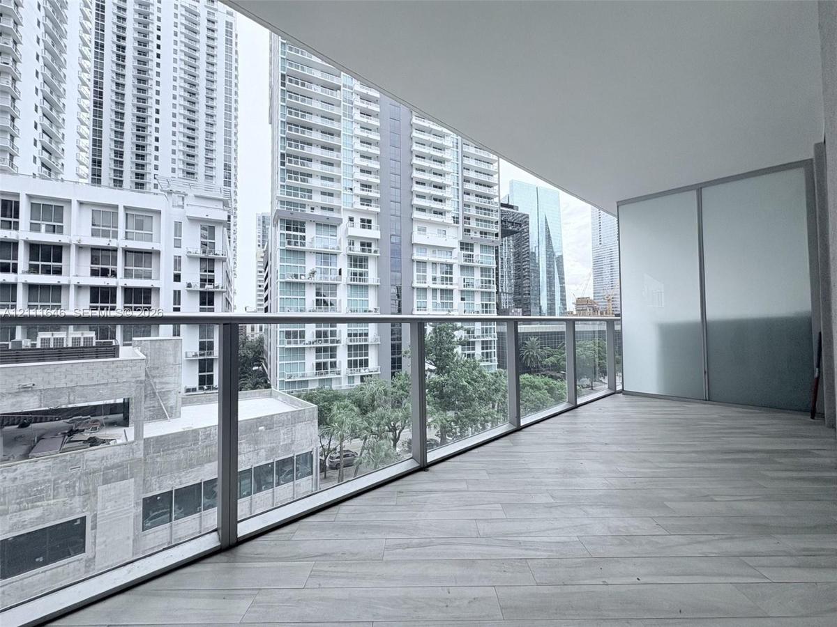 Covered balcony featuring wood-finish tile flooring, glass panel railings, and frosted privacy screening
