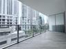 Covered balcony featuring wood-finish tile flooring, glass panel railings, and frosted privacy screening