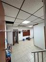 Interior space featuring grid-pattern acoustic drop ceiling tiles, integrated recessed lighting, and light-toned ceramic tile flooring