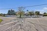 Corner lot property featuring a perimeter masonry wall with decorative accents, mature landscaping, and established trees