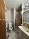 Bathroom featuring a vanity with integrated sink, brass-tone hardware, a wall-mounted medicine cabinet with integrated lighting, a stand-up shower enc