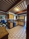 Kitchen featuring wood cabinetry, integrated built-in appliances, a tiled backsplash, exposed ceiling beams, and patterned tile flooring
