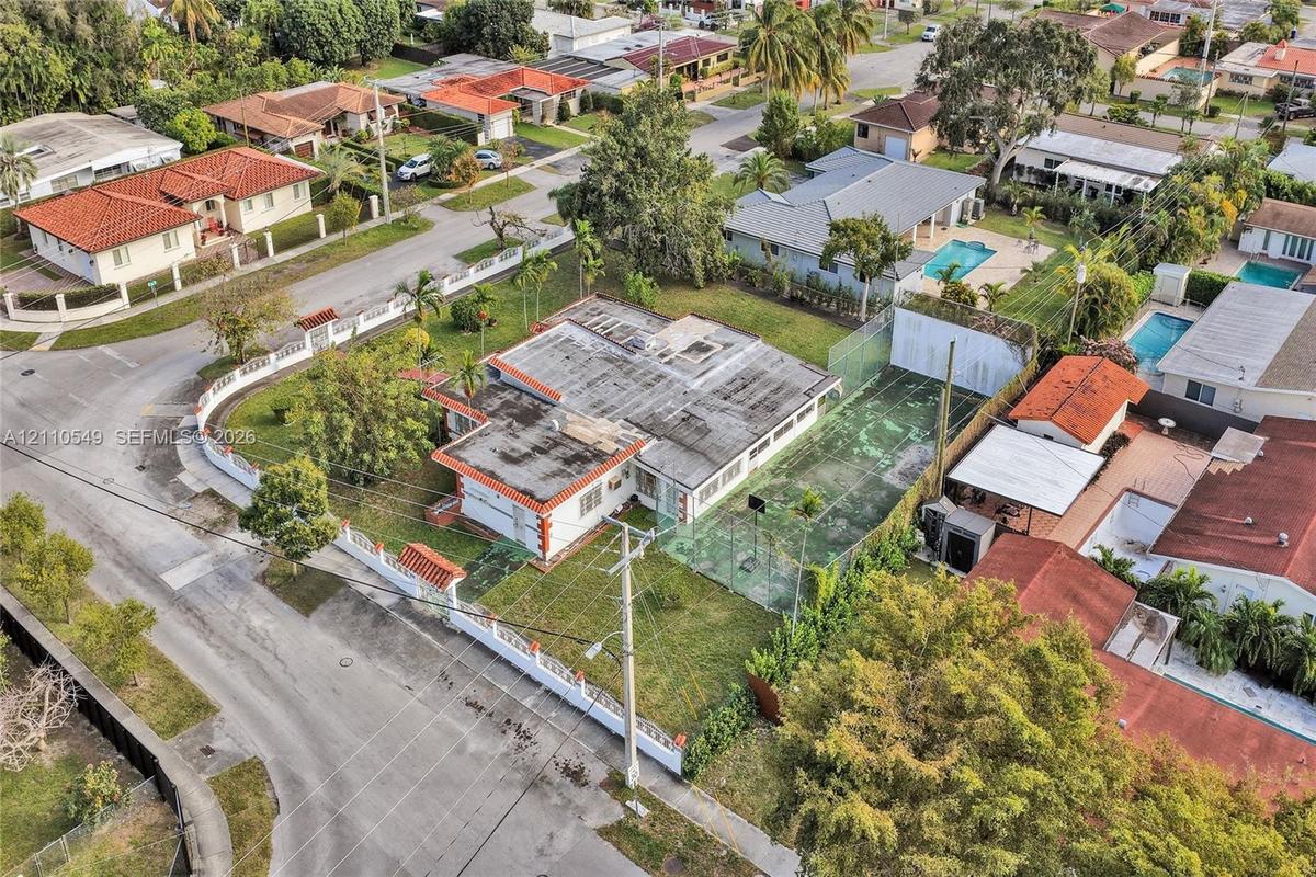 Aerial perspective featuring a corner lot property with a private fenced tennis court and a perimeter masonry wall