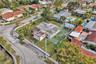 Aerial perspective featuring a corner lot property with a private fenced tennis court and a perimeter masonry wall