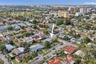 Aerial perspective of a residential property featuring a corner lot, mature landscaping, fenced perimeter, and driveway