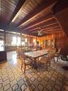 Exposed wood beam ceiling, wood paneled walls, patterned tile flooring, and a ceiling fan with integrated lighting