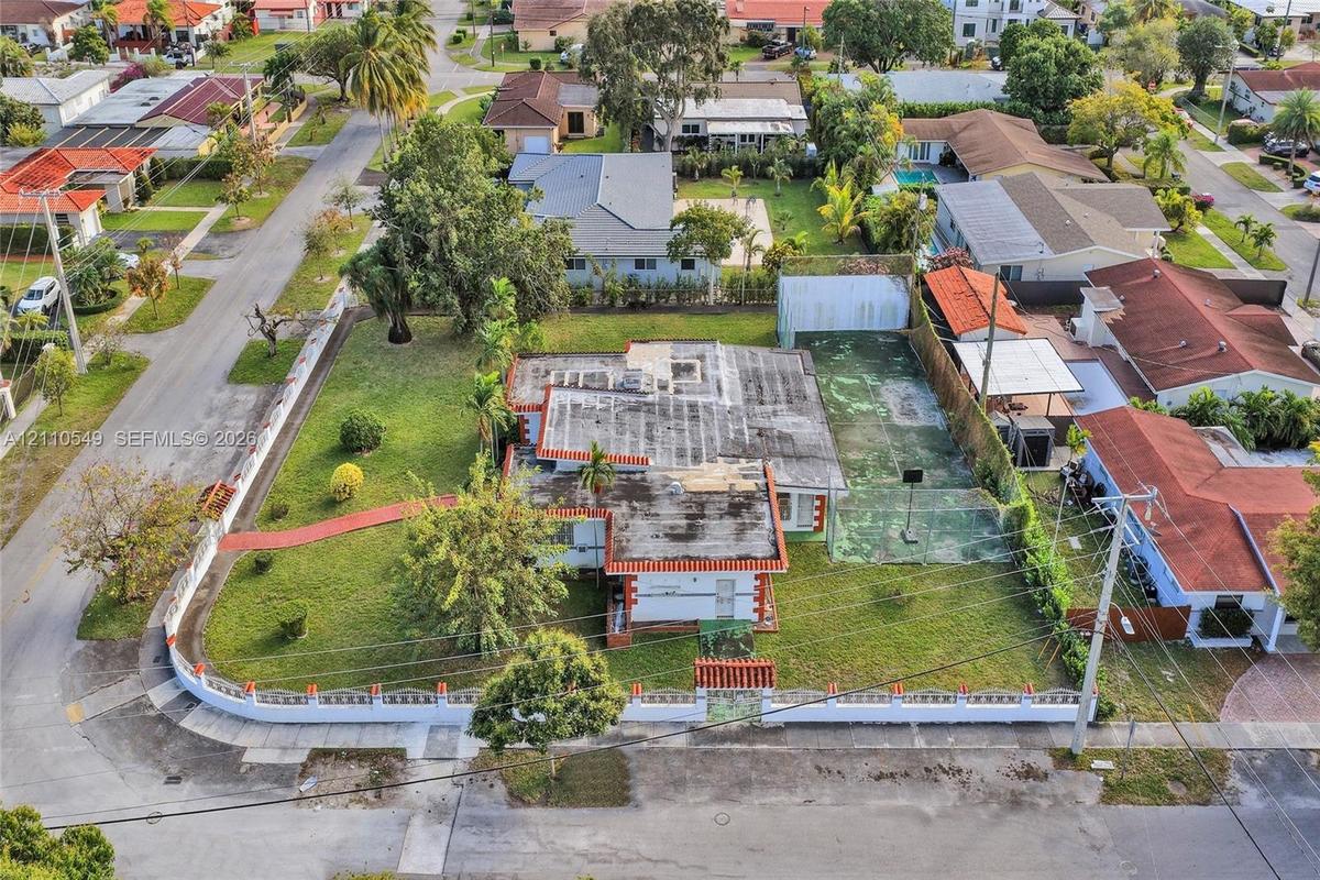 Corner lot featuring a perimeter wall with decorative accents, an expansive yard, and a dedicated hard-surface sports court