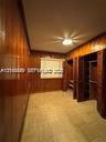 Room featuring vertical wood-paneled walls, tile flooring, recessed ceiling lighting, and built-in closet storage with louvered doors