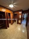 Wood-paneled walls, tile flooring, built-in storage closets, and a flush-mount ceiling light fixture