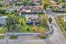 Corner lot property featuring a masonry perimeter wall, paved walkway, mature trees, and an enclosed hardscaped recreational area
