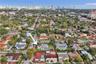 Aerial perspective of residential property featuring a flat-roof structure, expansive lot, and proximity to the urban skyline