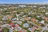 Aerial perspective of a corner lot residence featuring a screened-in rear patio, mature landscaping, and a fenced yard