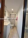 White vanity with a rectangular sink, neutral tile flooring, recessed ceiling lighting, and a bathtub with a shower enclosure
