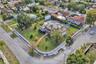 Corner lot property featuring a wraparound masonry perimeter wall, expansive manicured lawn, established landscaping, and paved walkway