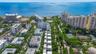 Aerial perspective of a coastal residential community featuring multiple high-rise structures, landscaped green space, tennis courts, and immediate pr