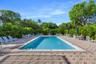In-ground rectangular swimming pool with integrated stairs, surrounded by a herringbone-patterned paver deck and mature perimeter landscaping