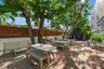 Outdoor patio featuring herringbone-pattern brick paving, vertical wood-plank perimeter fencing, and mature trees