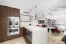 Kitchen featuring wood-finish cabinetry, a waterfall-edge island with stone countertop, stainless steel double wall oven, polished pendant lighting, a