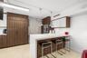 Kitchen featuring a waterfall-edge stone countertop, custom cabinetry with wood-finish and white high-gloss doors, stainless steel wall-mounted oven, 