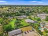 Expansive lot featuring a gravel driveway, mature trees, and open green space