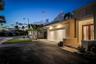 Exterior facade featuring a multi-panel garage door, paved driveway, and double-entry doors with glass inserts