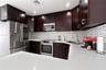 Kitchen featuring dark wood cabinetry, quartz countertops, a multi-tonal mosaic tile backsplash, and stainless steel appliances including a microwave,