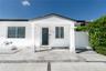 Exterior facade featuring a covered entryway, stone-tile porch, full-glass front door, and white privacy fencing
