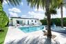 Outdoor swimming pool with integrated spa, stone-tile decking, mature palm trees, and perimeter privacy hedges